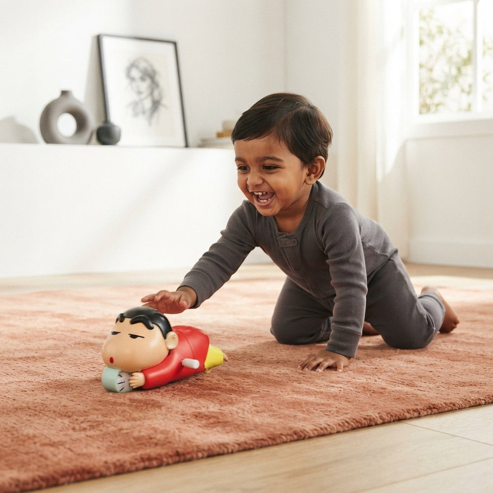 An Indian toddler crawling on a terracotta rug while interacting with a Shinchan crawling toy in a bright living room.